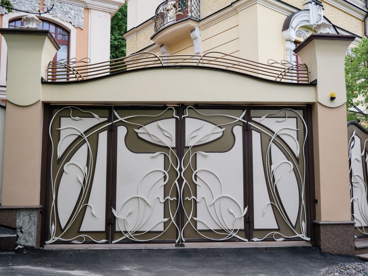 Elegant Art Nouveau gate with intricate floral design in a city architecture setting.